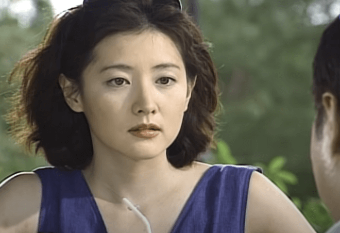 韓国女優イ・ヨンエが2000年ドラマ「火花」に出演した際のワンシーン画像。
髪は前髪無しのボブヘアでウェーブがかかっている。
サングラスを頭にかけていて、ネイビーのノースリーブを着用している。
真剣なまなざしで会話をしている様子。